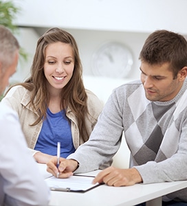 couple signing paperwork for funding their adoption